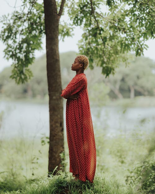 Woman with Dyed, Short Hair Standing in Red Dress near Tree