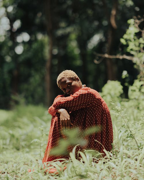 Woman in Spotted Red Dress Sitting on Grass in Forest