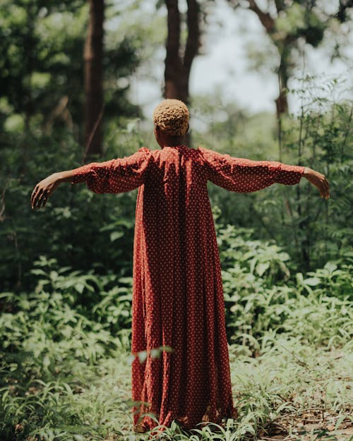 Woman with Dyed, Blonde Hair Standing with Arms Stretched in Forest