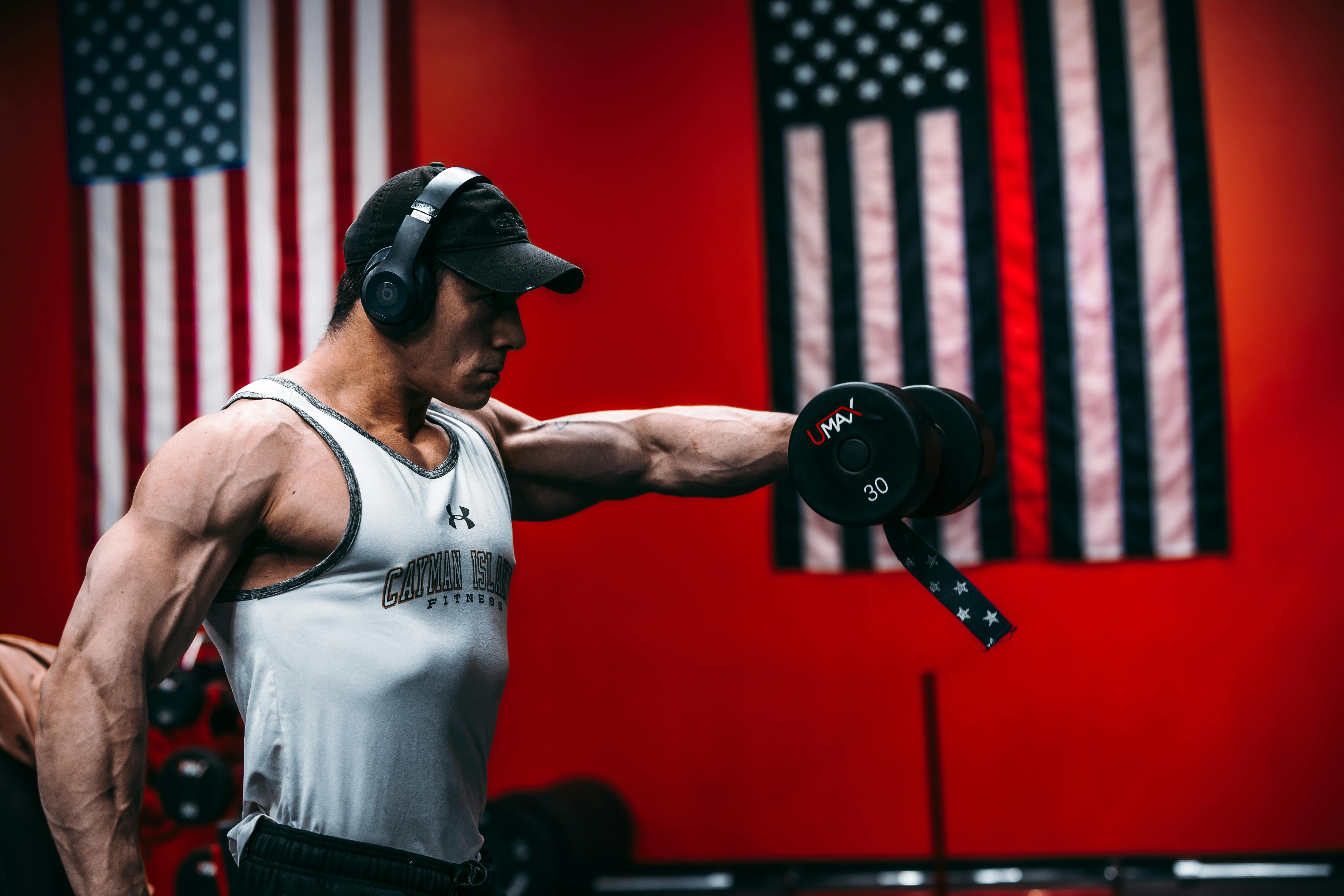 Muscular man lifting dumbbell in gym, showcasing strength and fitness.