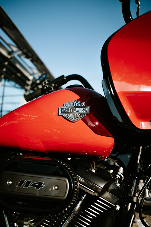 Free Vibrant red Harley-Davidson motorcycle fuel tank and engine detail captured outdoors. Stock Photo