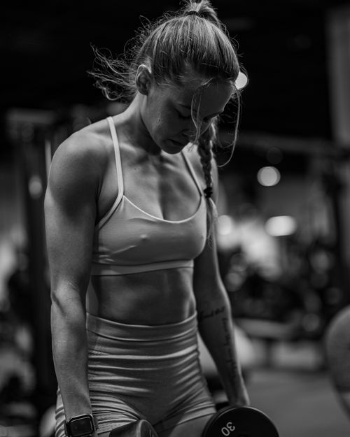 Free Black and white photo of a woman lifting weights in a gym, showcasing strength and determination. Stock Photo