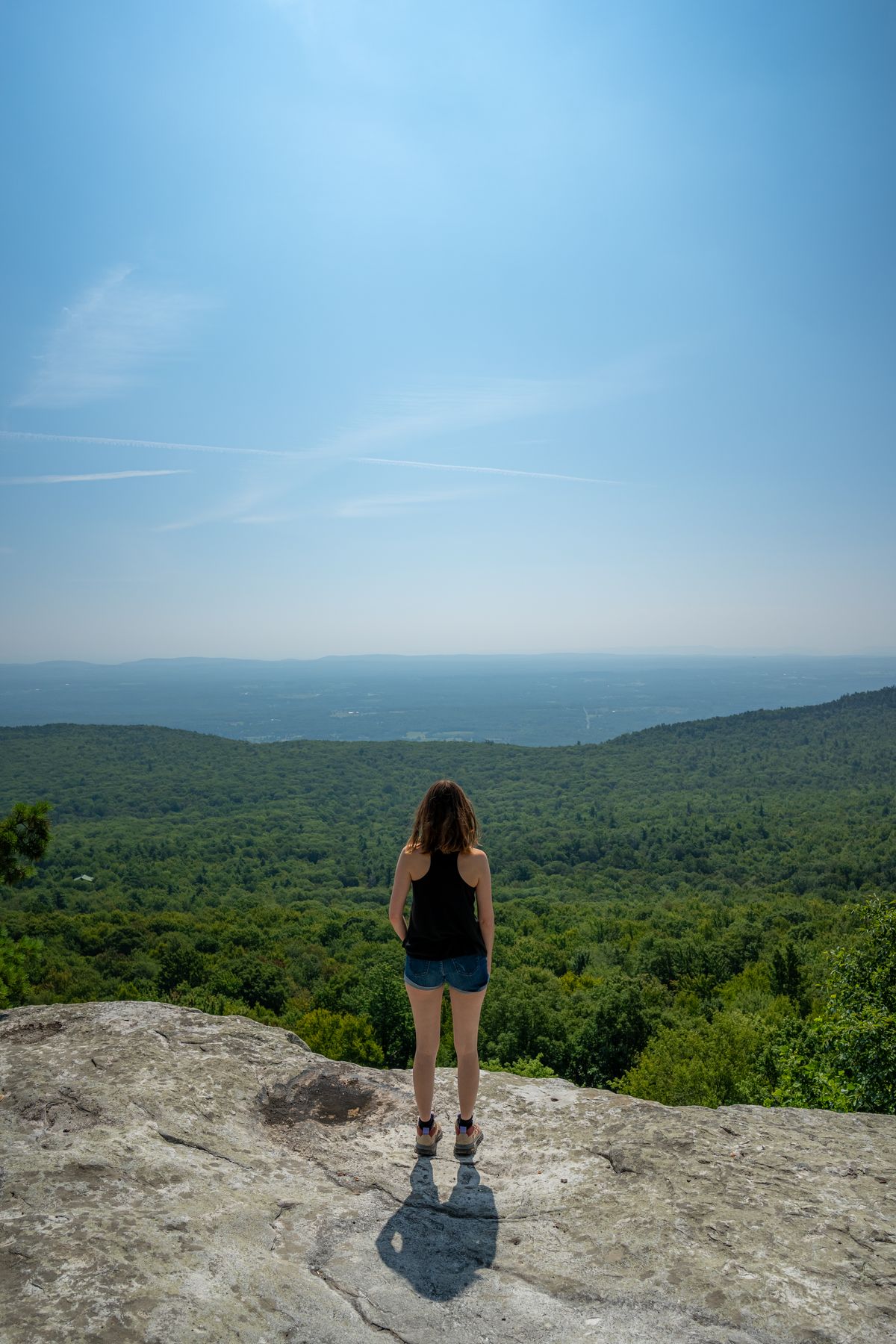 Woman in White Shirt Sitting on a Rocky Cliff · Free Stock Photo