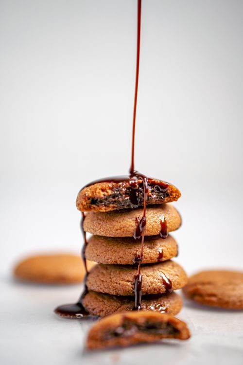 Free Delicious stack of cookies drizzled with chocolate sauce, creating a tempting food scene perfect for culinary photography. Stock Photo