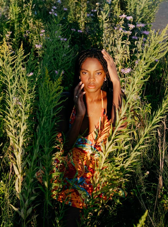 A woman in a floral dress is standing in tall grass