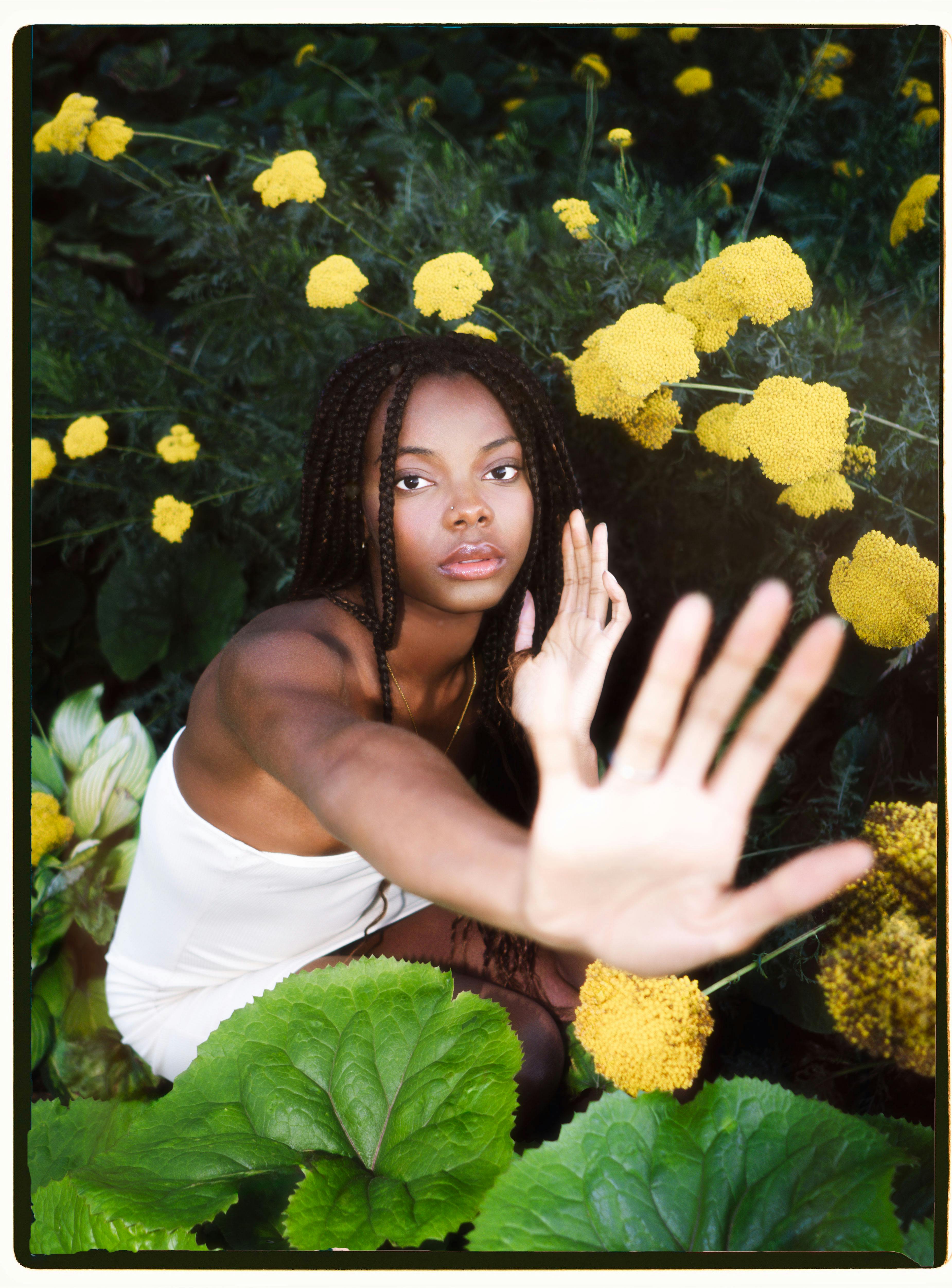 A striking portrait of a woman in a garden with yellow flowers, showcasing natural beauty and vibrant flora.