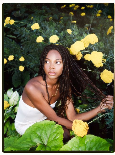 Elegant portrait of a woman surrounded by vibrant summer flowers in Montréal park.