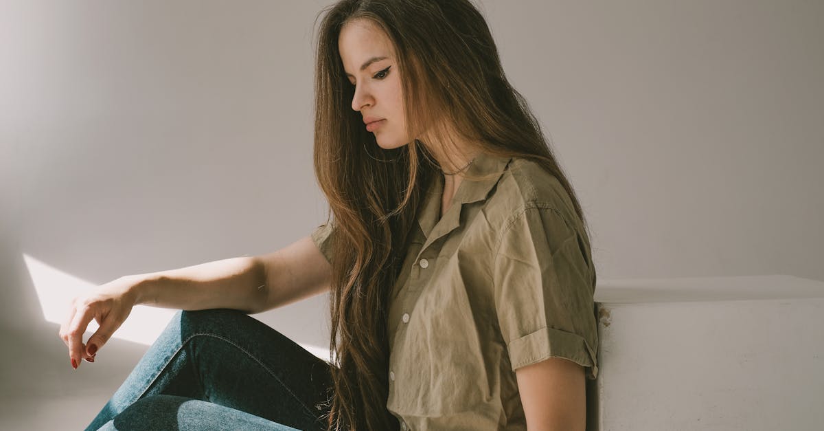 a sad girl with long hair sitting on a floor thinking