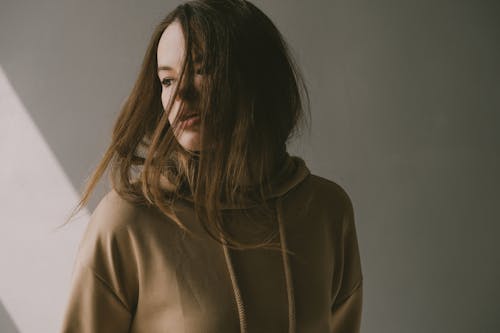 a girl with long hair wearing beige hoodie in a movement