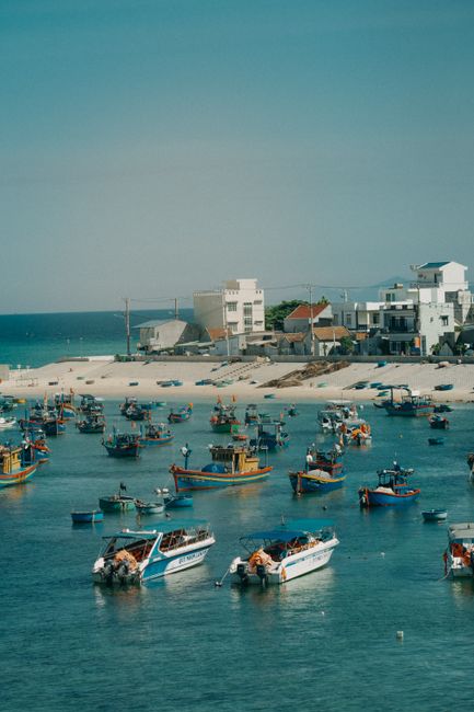 A scenic view of vibrant boats in a seaside village harbor with clear blue waters.