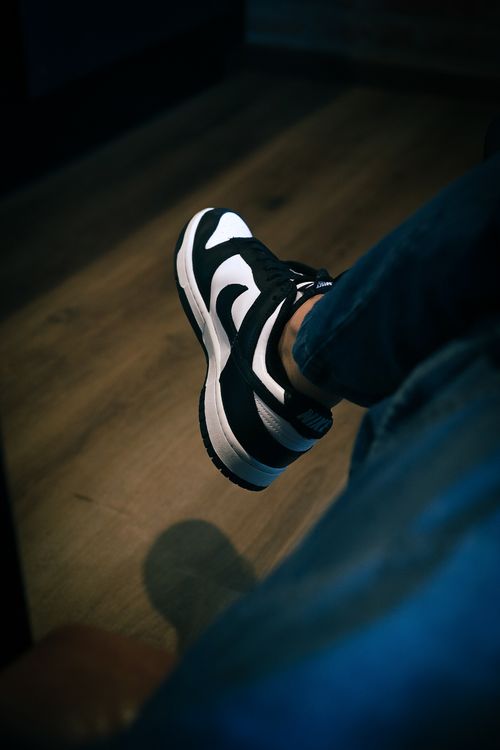 Free Close-up of black and white sneakers on a wooden floor, captured indoors with selective focus. Stock Photo