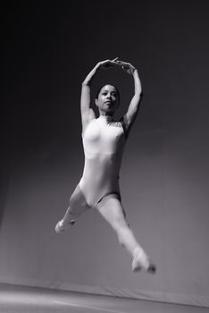 A skilled ballerina captured mid-leap, emphasizing her grace and elegance in a monochrome setting.