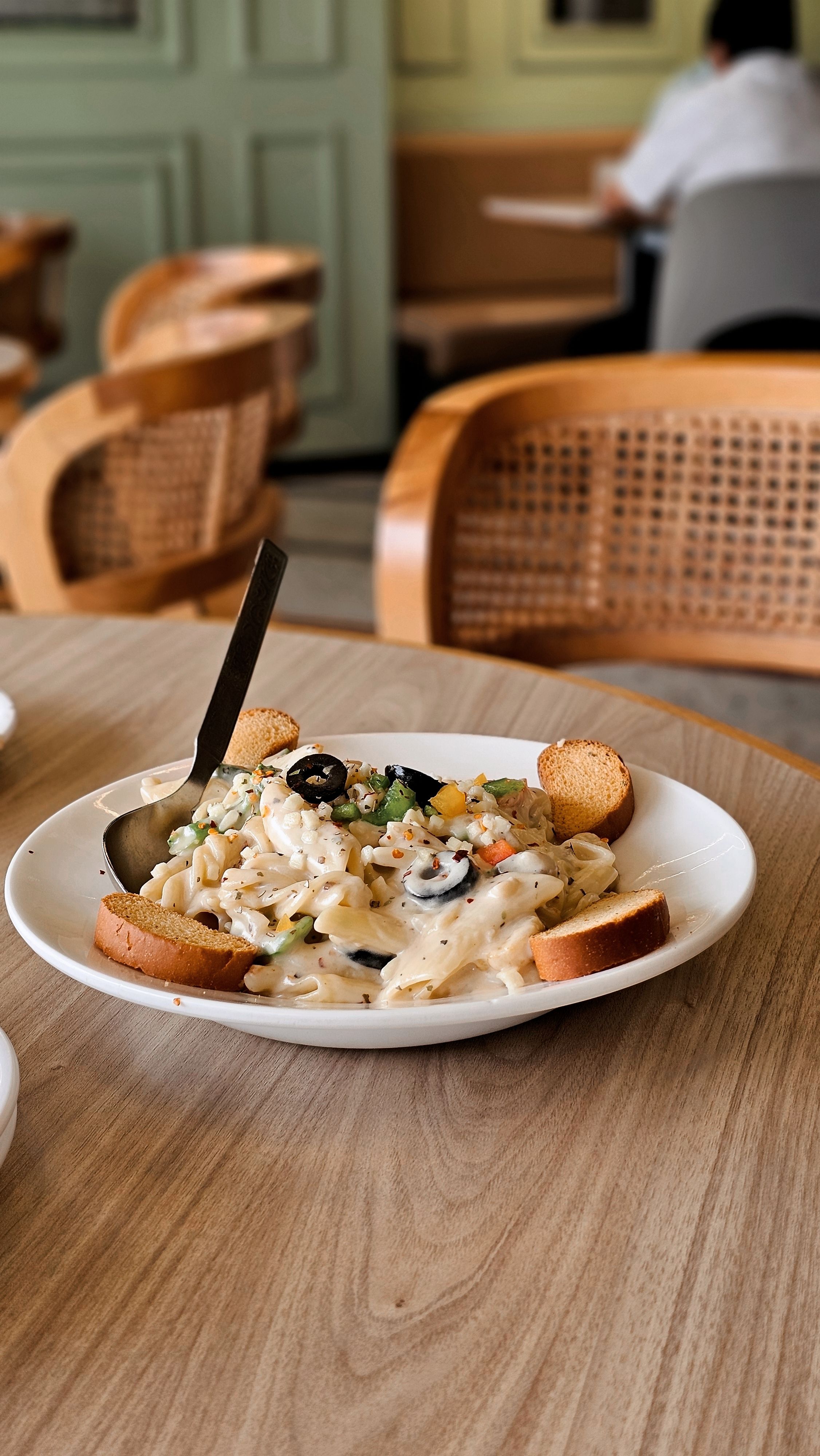 A creamy pasta dish served with bread on a wooden table in a cozy café setting.