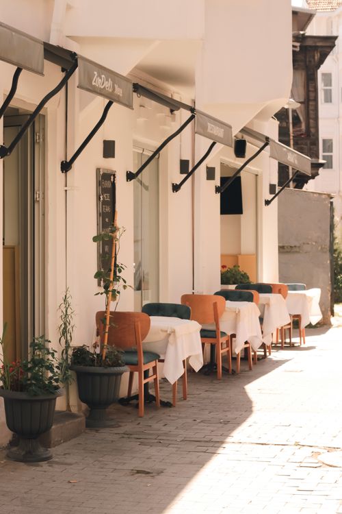 Free Sunlit outdoor cafe with empty tables lined along a charming street in Arnavutköy, Istanbul. Stock Photo