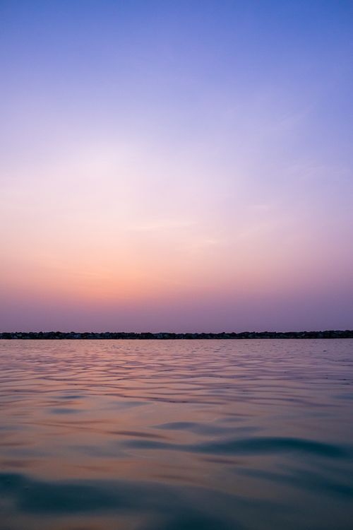Free Peaceful sunset over gently rippling open water with a purple sky Stock Photo