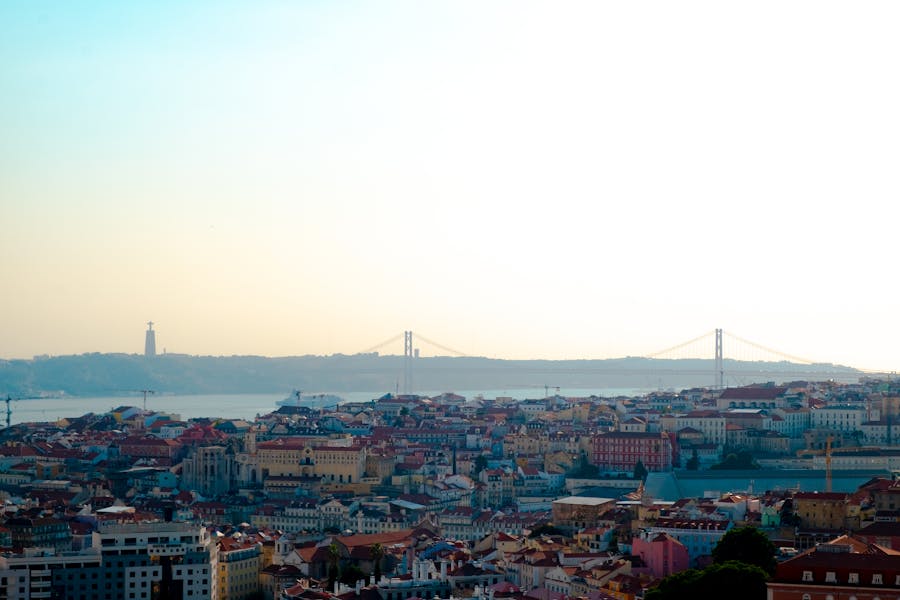 Panoramic view of Lisbon skyline highlighting the iconic Ponte 25 de Abril bridge at sunset