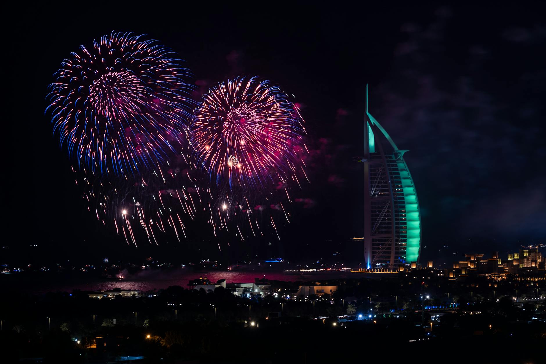 Vibrant fireworks illuminate the night sky over Dubai's iconic Burj Al Arab.