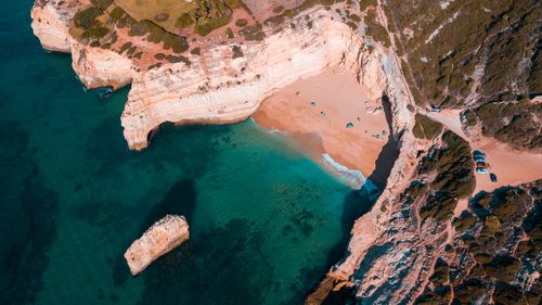 Free Breathtaking aerial shot of sunlit Algarve beach with cliffs and turquoise sea. Stock Photo
