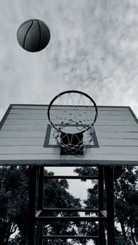 A basketball soaring towards the hoop, captured in black and white for dramatic effect.