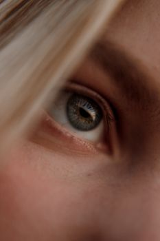 Intimate close-up of a blonde woman's green eye, focusing on detail and expression.