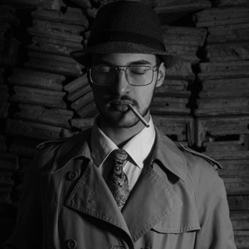Black and white portrait of a man in a trench coat smoking a cigarette. Vintage fashion vibe.