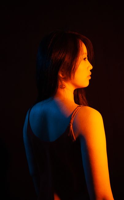 Studio portrait of a woman in dramatic lighting with vibrant colors and dark background.