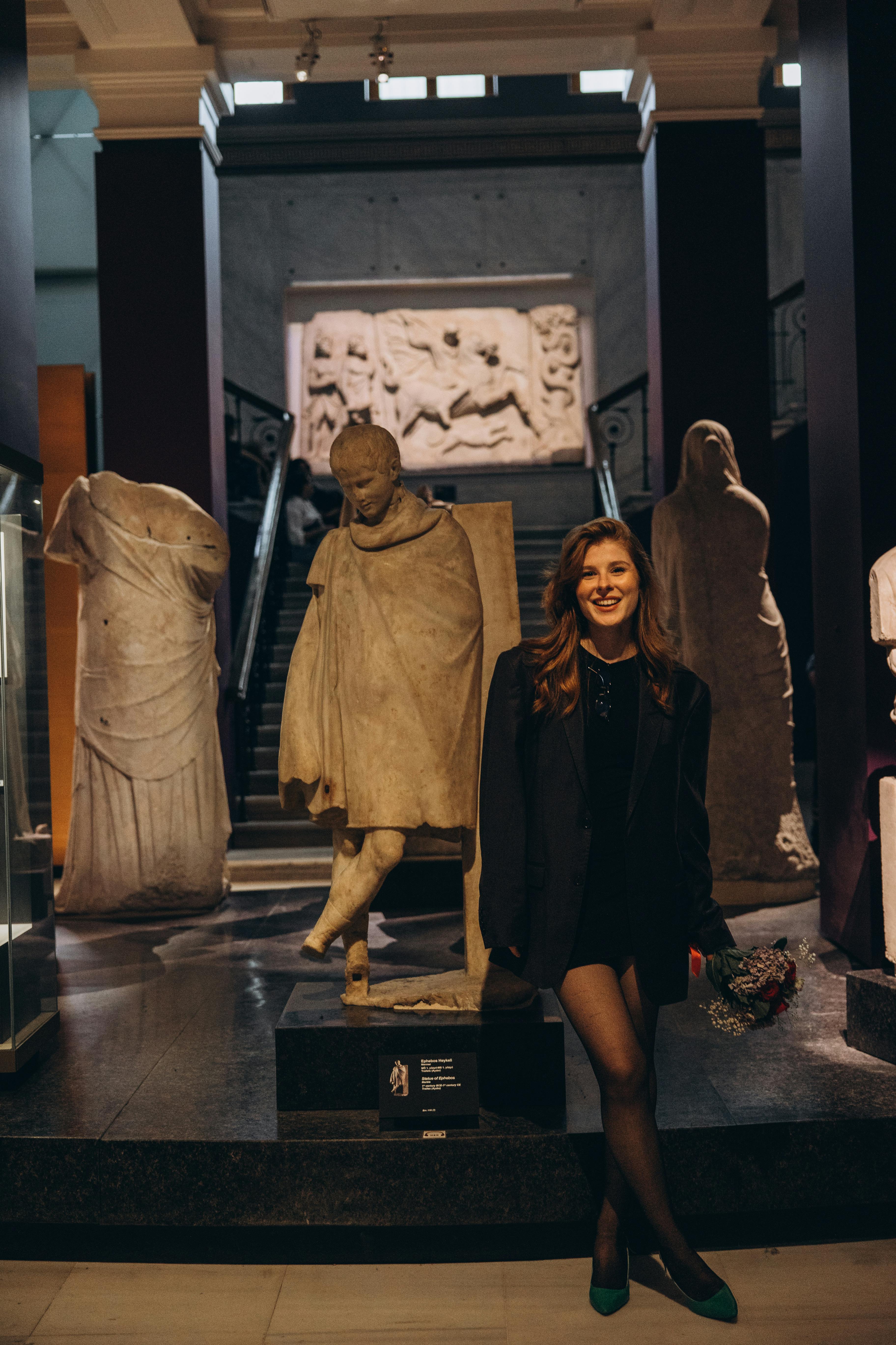 a woman standing in front of a museum with statues