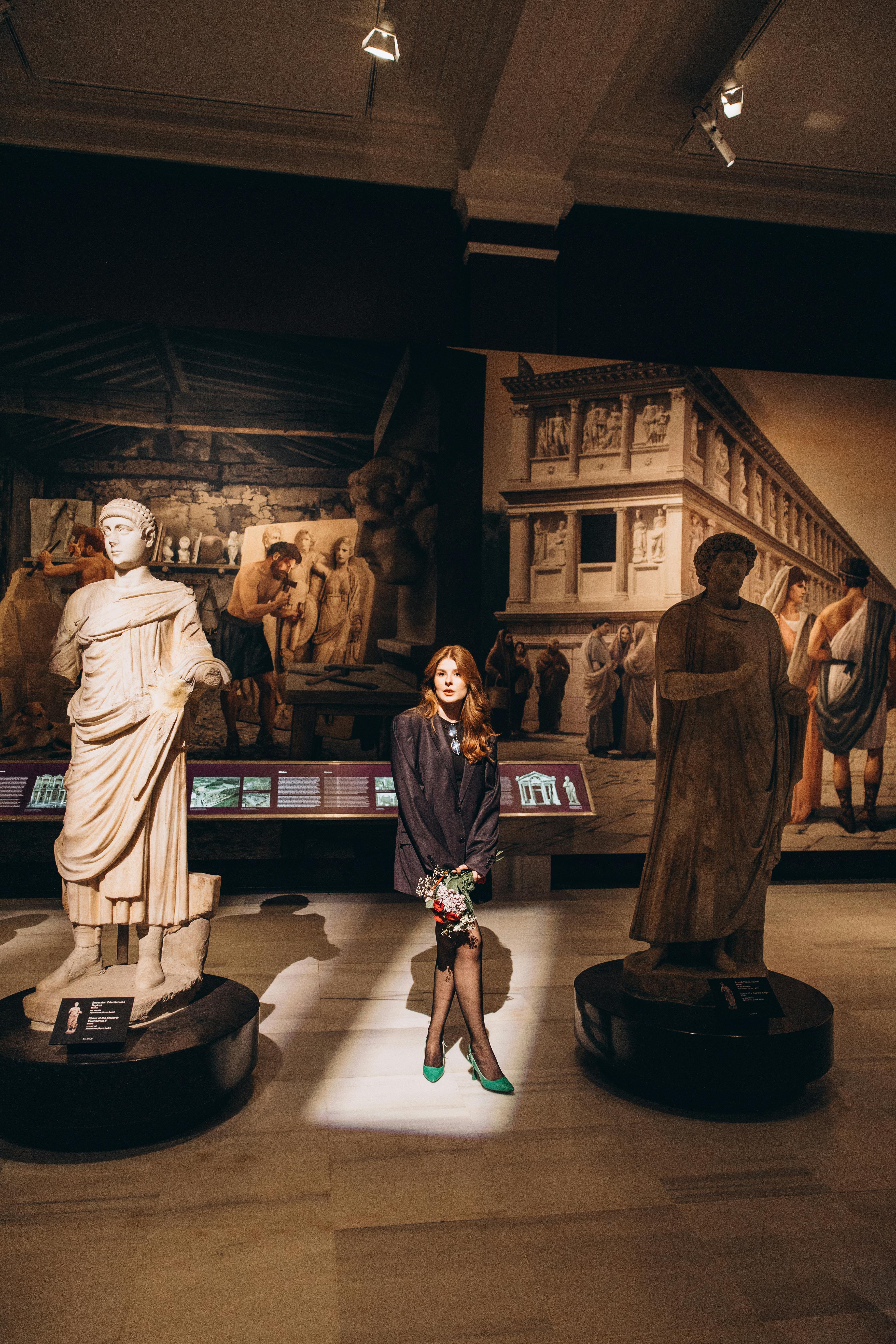 a woman standing in front of statues in a museum