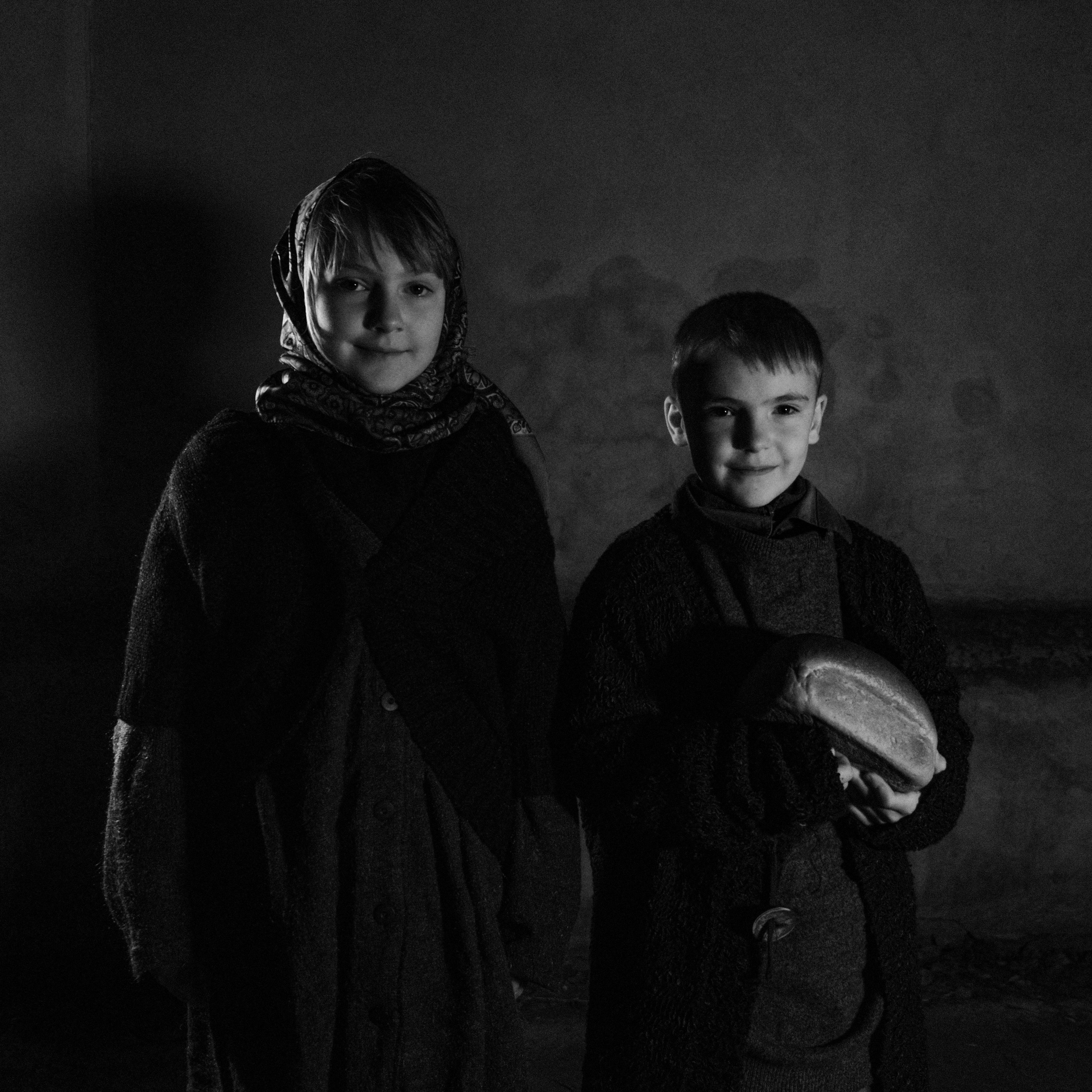 black and white picture of a young girl and boy in warm clothing