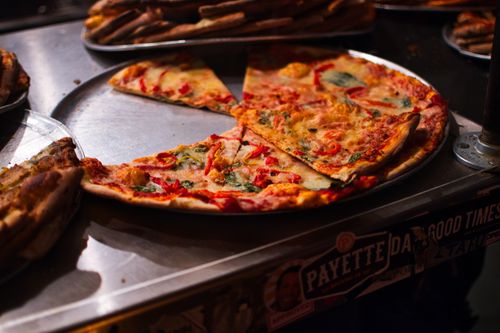 Free A mouth-watering view of vegetarian pizza slices with toppings on a metal tray, ready to serve. Stock Photo