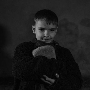 A black and white portrait of a young boy holding a loaf of bread, conveying warmth and simplicity.