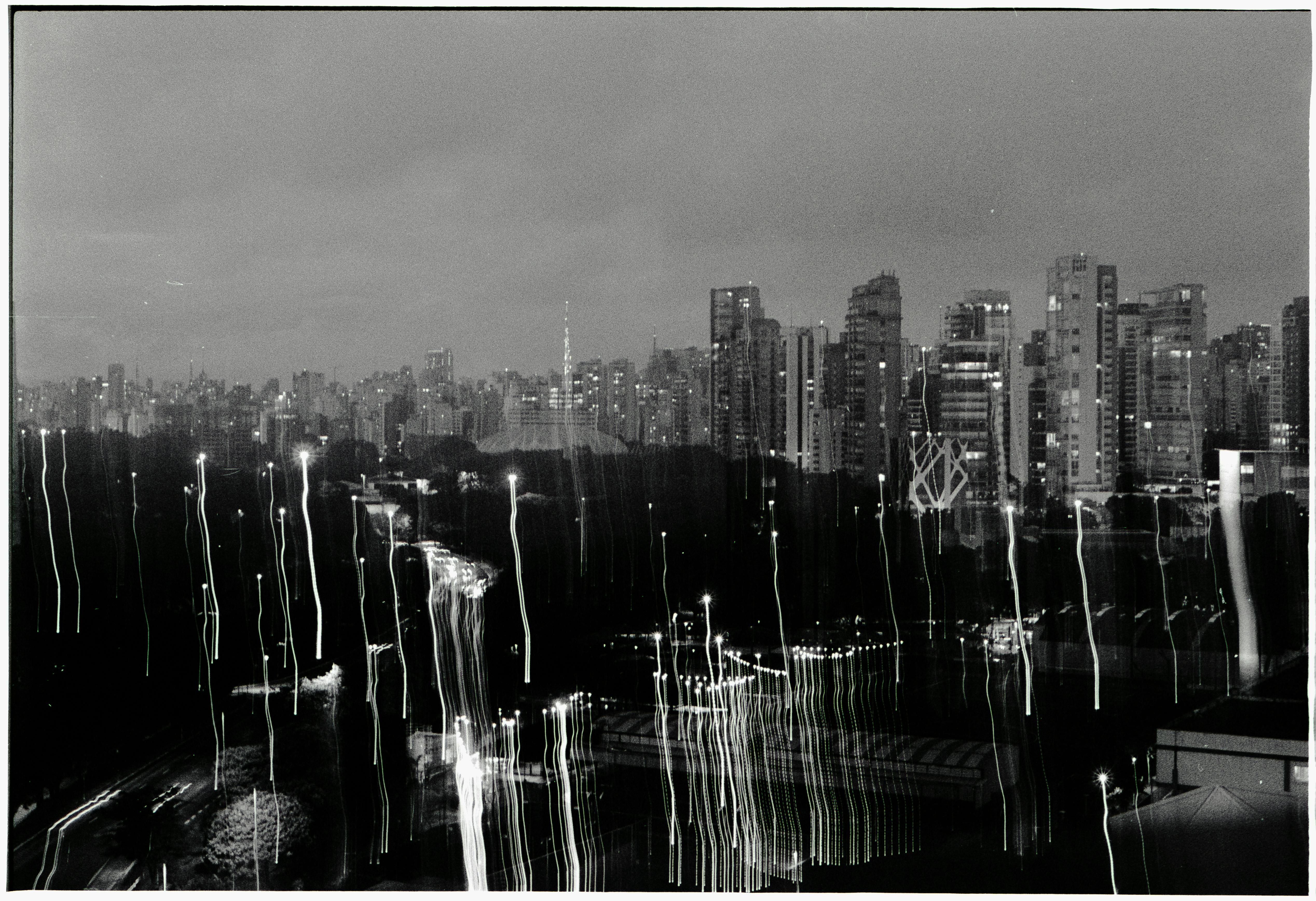 Black and white photo of a cityscape at night with light trails from moving vehicles.