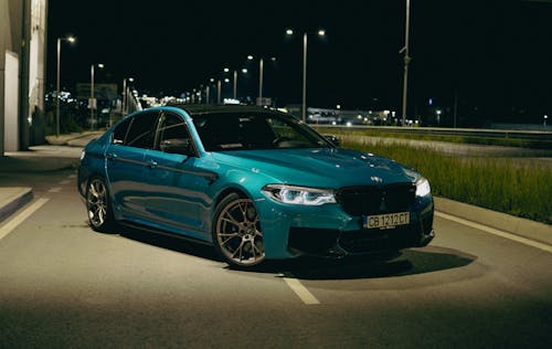 A Blue BMW M5 Parked on a Street at Night 