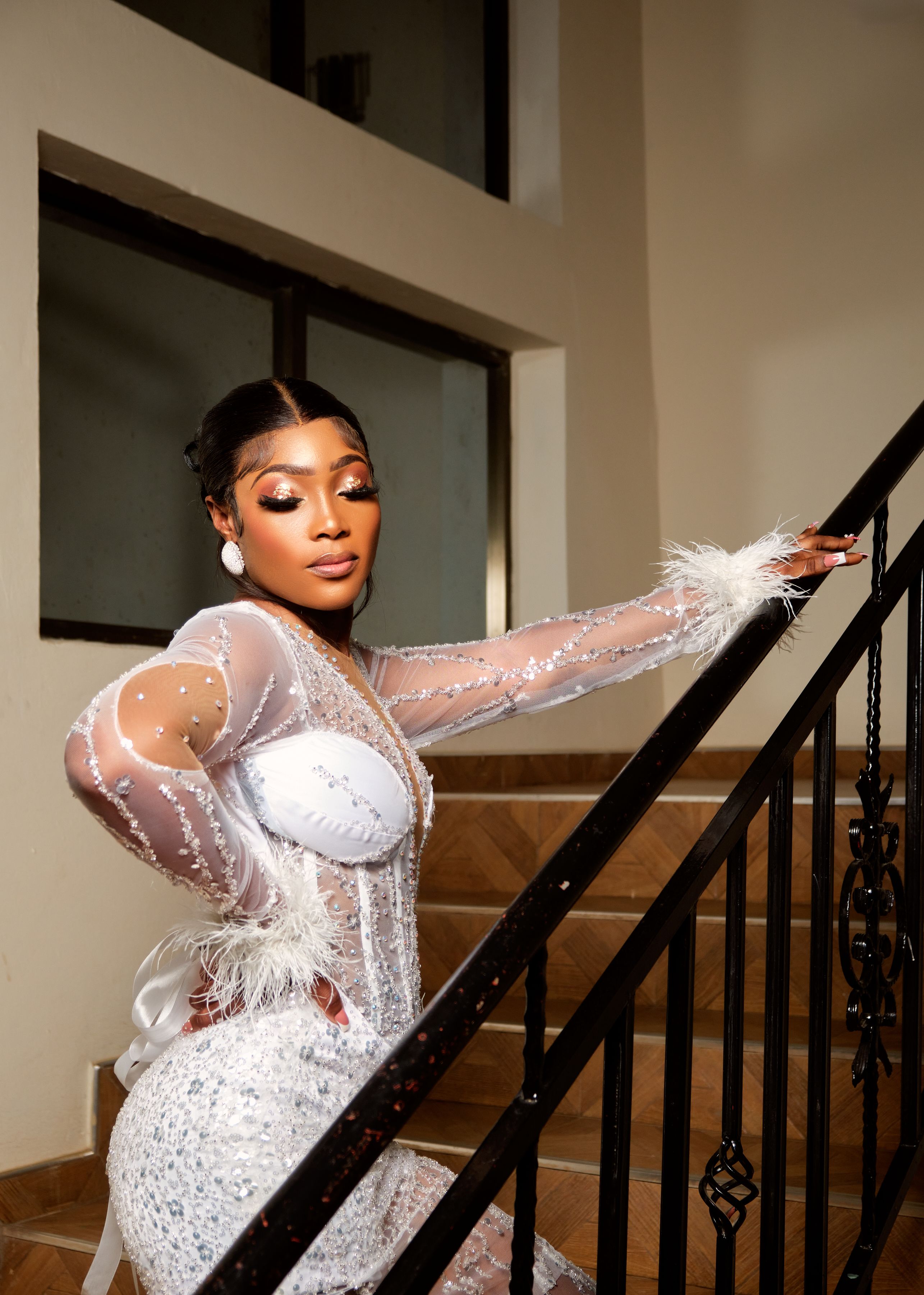 Stunning bride in a white gown posing gracefully indoors on a staircase.