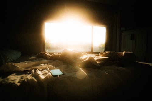 Free Bright Sunlight Shining through Window on a Messy Bed Stock Photo
