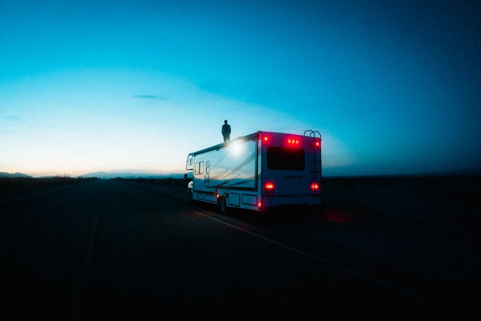Dramatic scene of a man standing on an RV at sunset in the Mojave Desert.