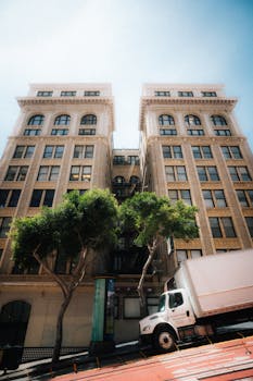 Low-angle view of a historic building and truck on a sunny San Francisco street.