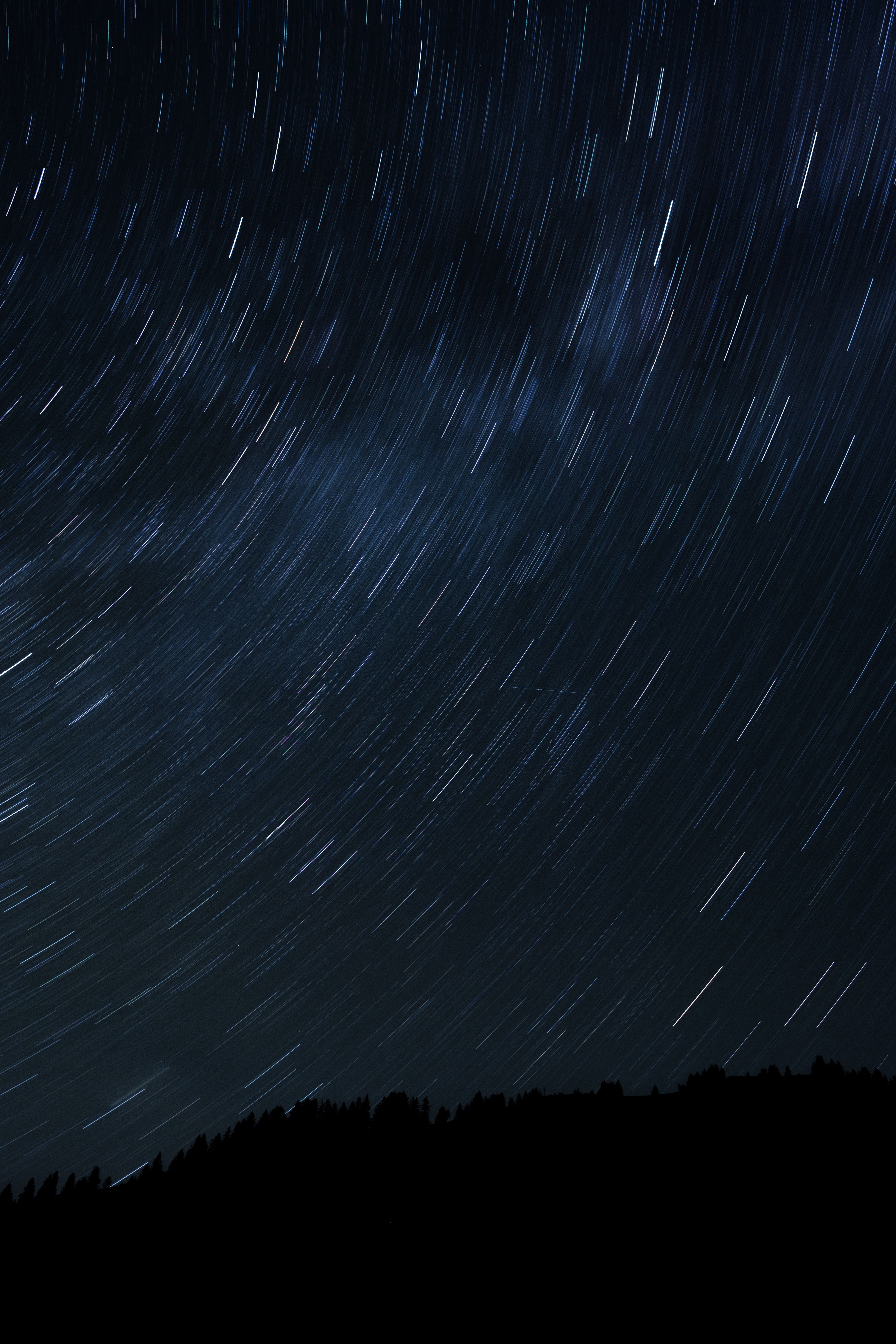 Long exposure captures star trails over mountains in Sonntag, Austria's clear night sky.