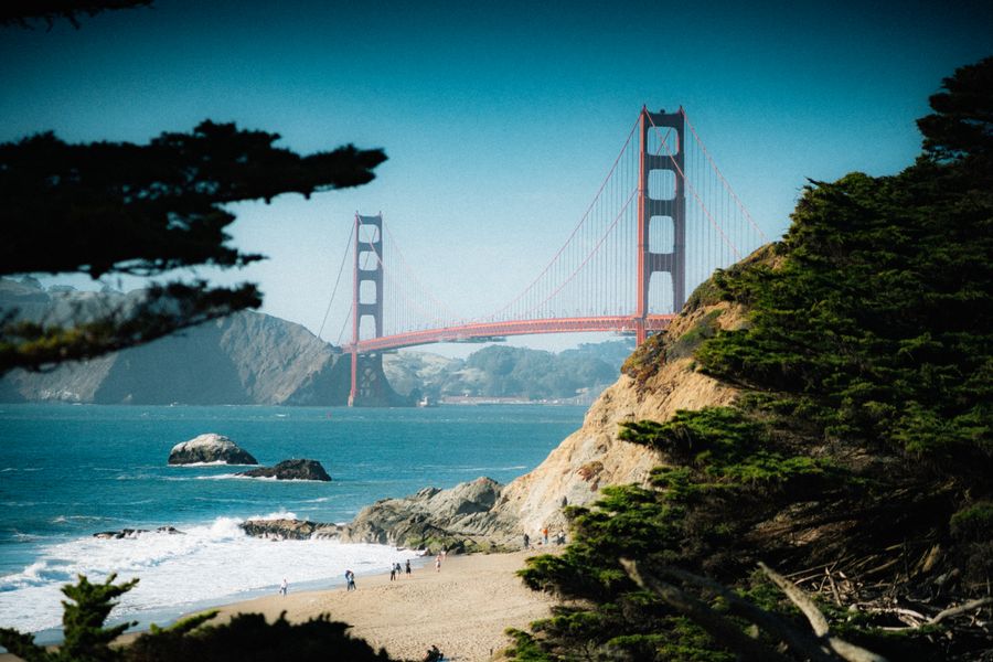 Golden Gate Bridge seen from a sandy beach with cliffs and trees in San Francisco