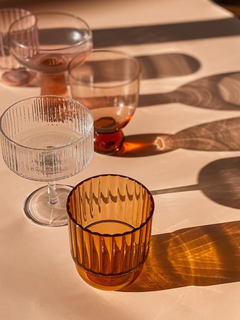 Elegant glassware casting bold shadows in warm sunlight on a table.