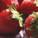 特写镜头下，新鲜多汁的草莓呈现出充满活力的红色和翠绿的叶子，完美诠释了健康小吃的主题