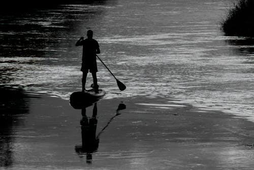 A man is standing on a paddle board in the water