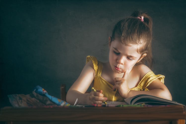 Girl Sitting By Table And Drawing