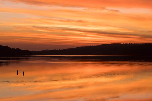 Free Experience the calmness of a serene sunset reflecting on a tranquil lake with an orange sky. Stock Photo