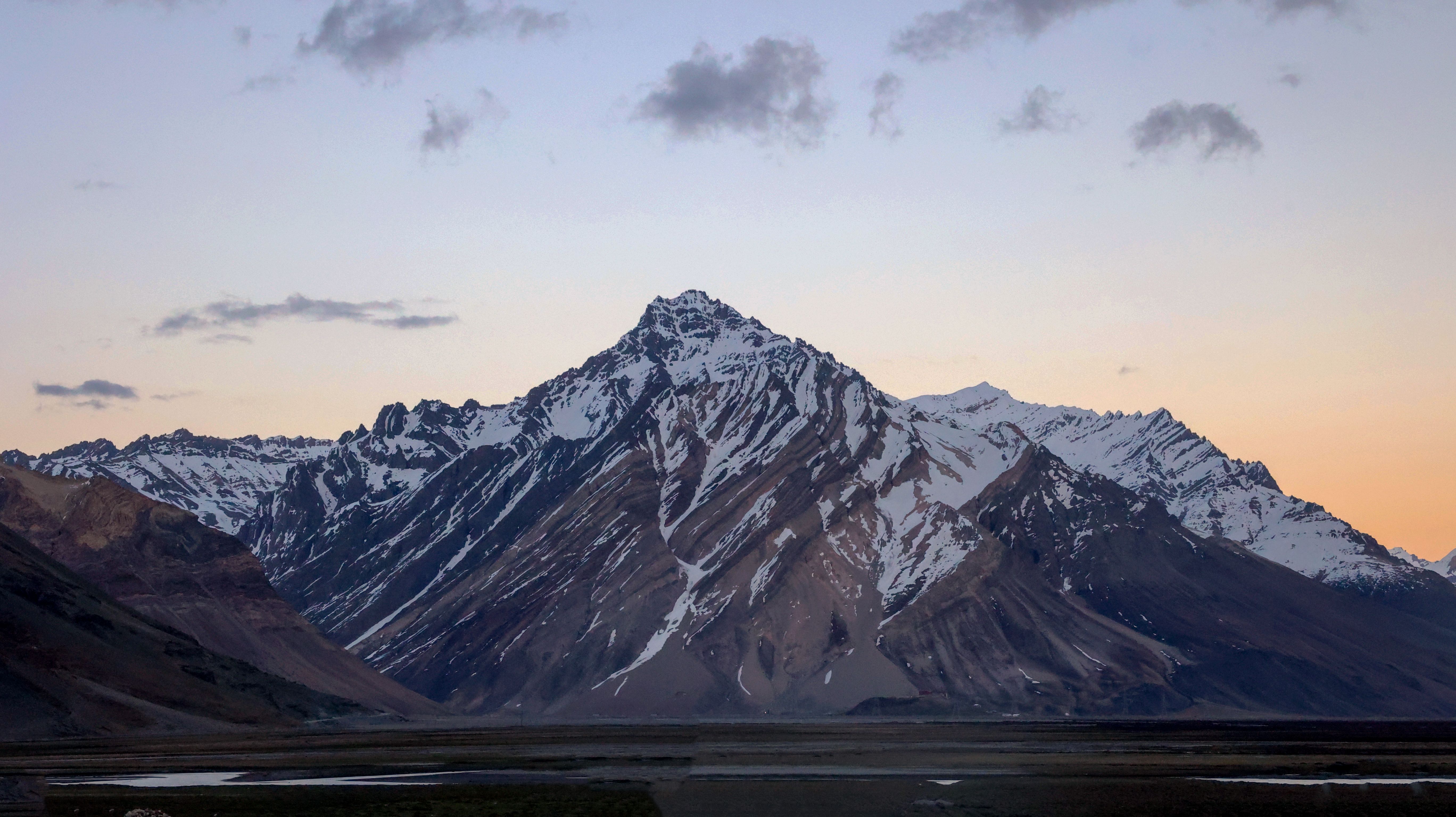 A mountain range with snow capped peaks at sunset · Free Stock Photo
