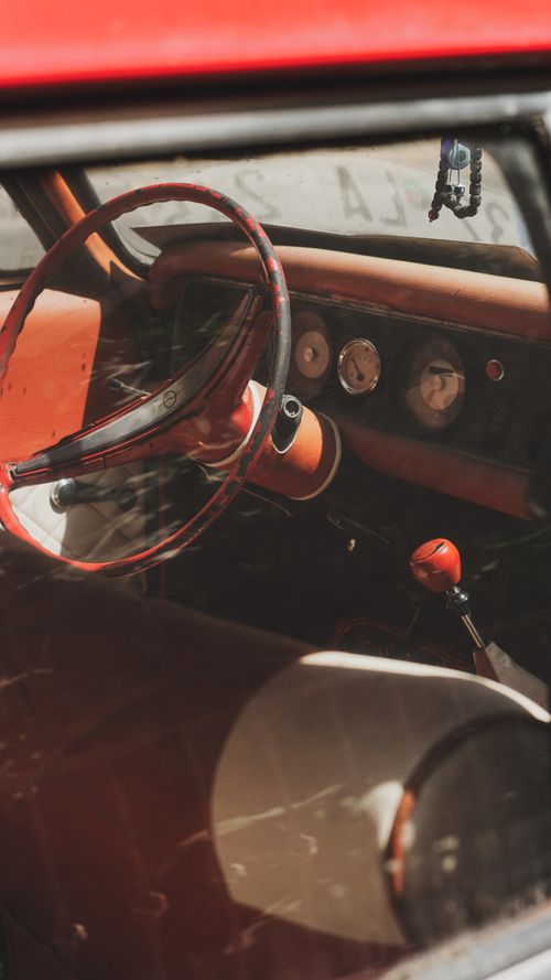 Free Close-up of a vintage car interior showcasing a red steering wheel and dashboard. Stock Photo
