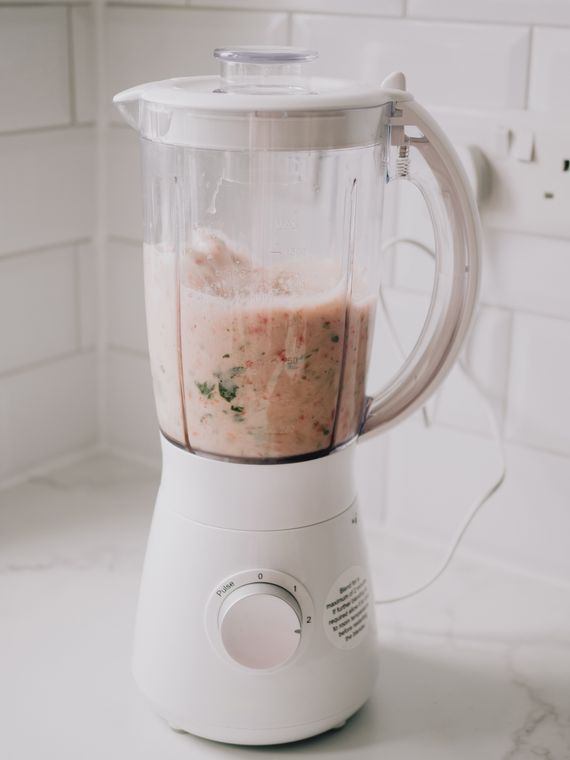 White countertop blender preparing a fresh smoothie in a clean kitchen