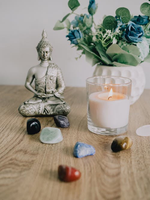 Free Buddha Figurine next to Crystals and Burning Candle Stock Photo