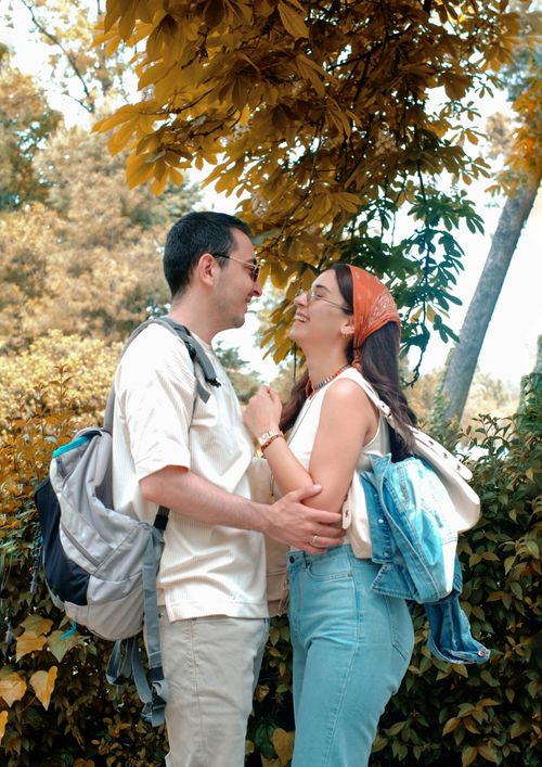 Free A happy couple with backpacks embracing outdoors under golden foliage on a sunny day. Stock Photo