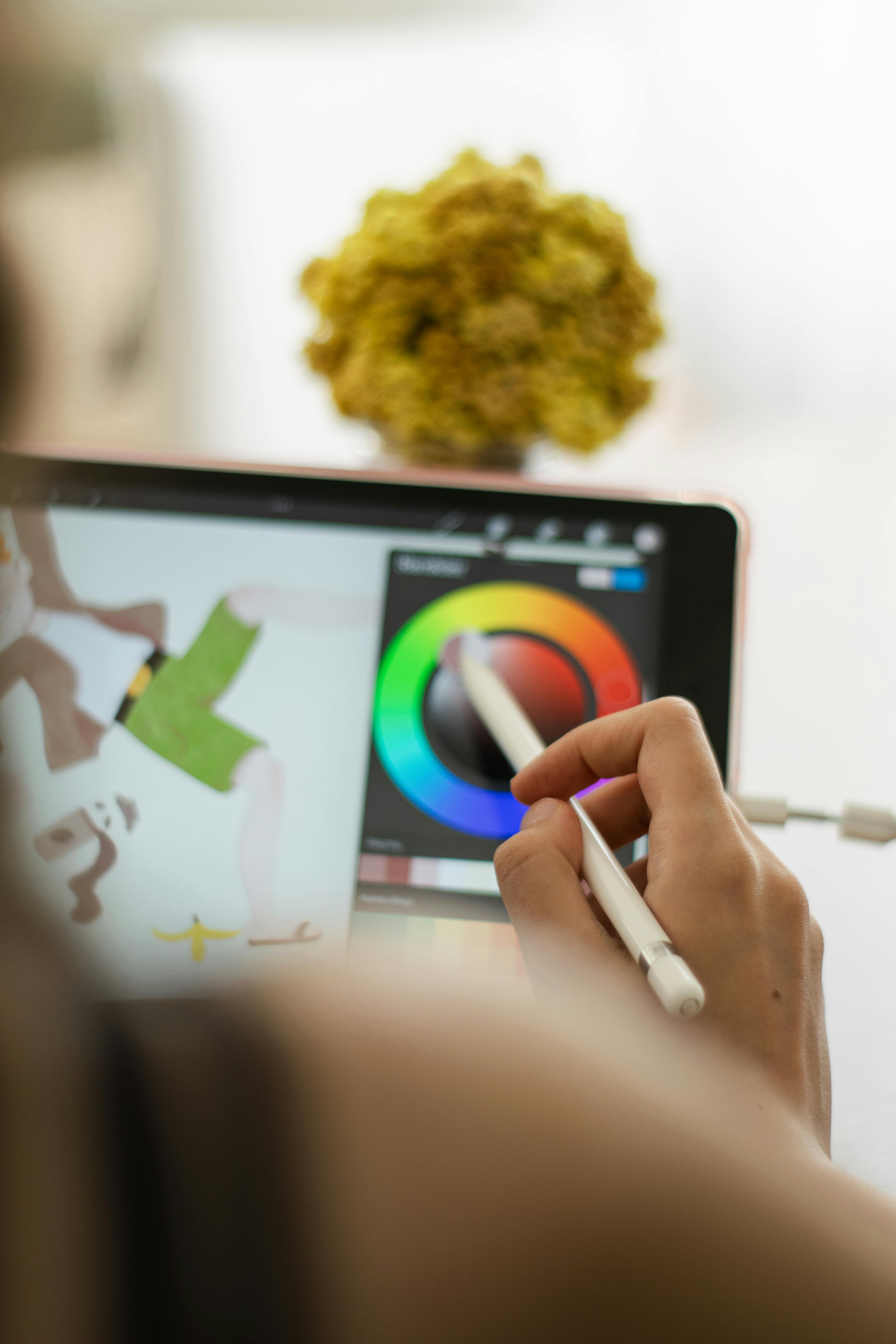 Close up of hands using a tablet to edit a digital graphic.